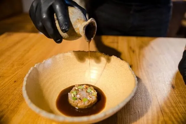 Berenjena a la llama, gamba blanca en grasa de txuleta madurada y caldo de cebollas asadas