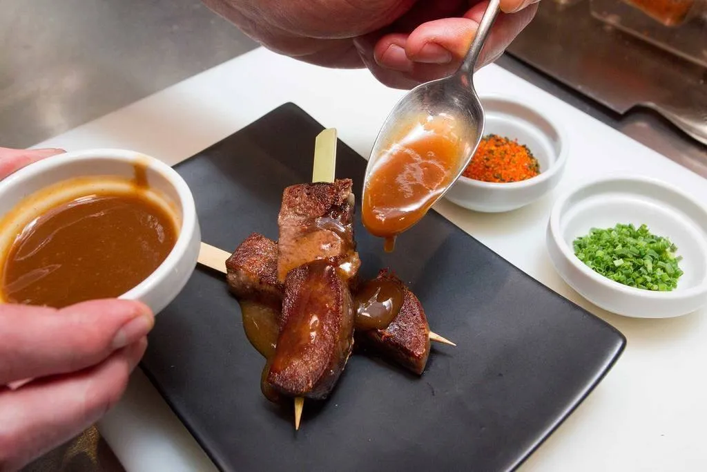 Emplatar los pinchos cruzados, salseándolos con el agua de la cocción espesada y decorarlos con el shichimi togarashi y el cebollino.