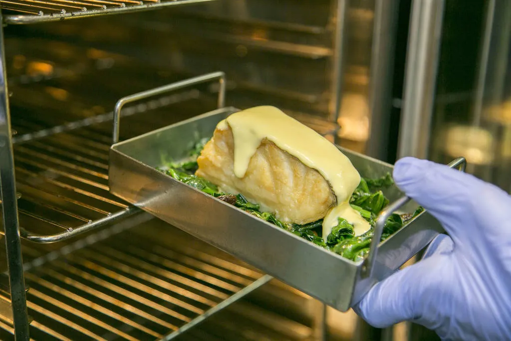 Cubrimos el fondo de un recipiente apto para el horno con las espinacas a la catalana, colocamos el bacalao encima de las mismas y lo cubrimos con el alioli. Gratinamos en el horno a 200 grados hasta que el alioli tenga un color ligeramente dorado.