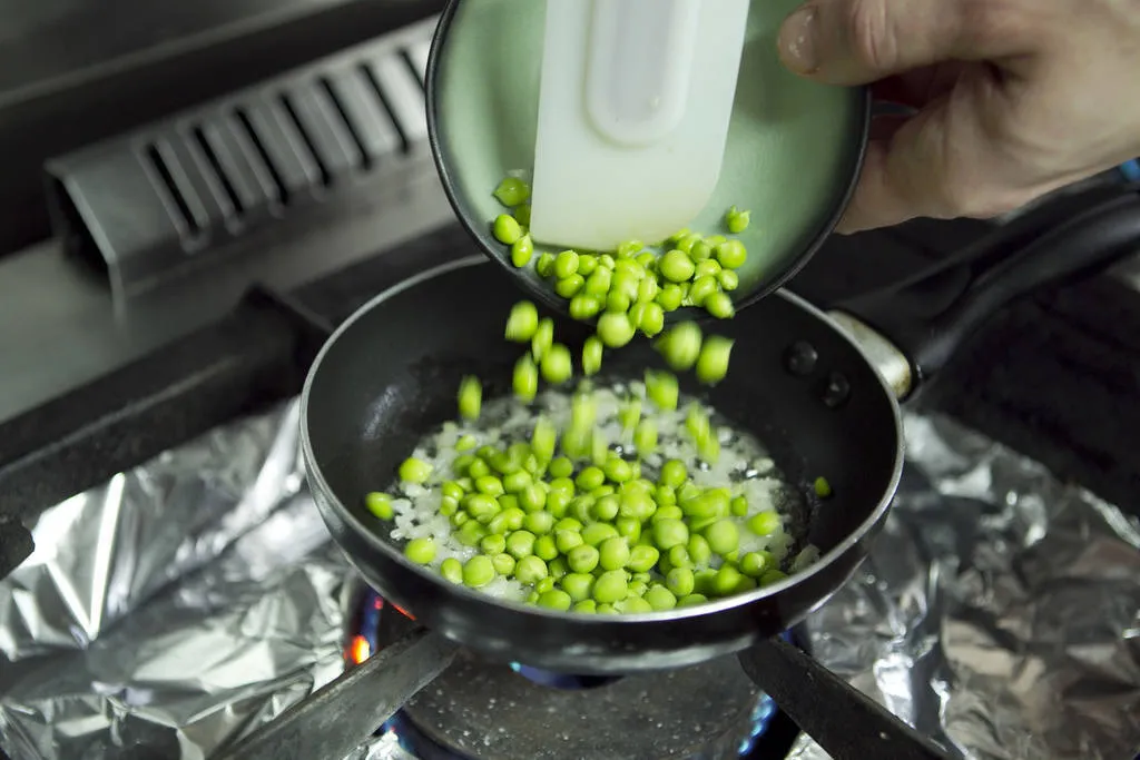 Sofreiremos una cebolleta picada con mantequilla sin coger color, añadiremos el guisante fresco, salpimentaremos y cubriremos con el agua de escaldar las vainas