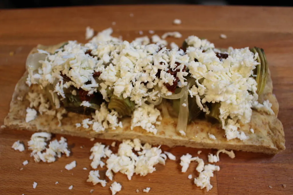 Coca salada con alcachofas, tomate seco y queso fresco