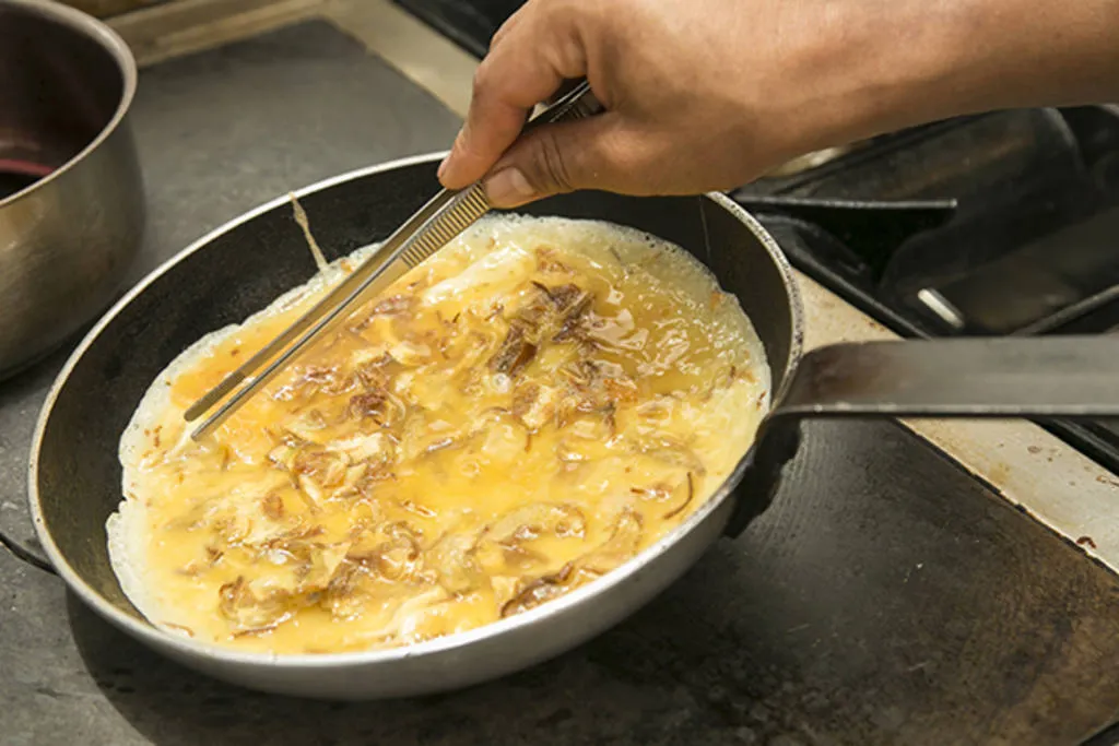 Tortilla abierta de chips de alcachofa, jamón ibérico y yema ahumada al romero