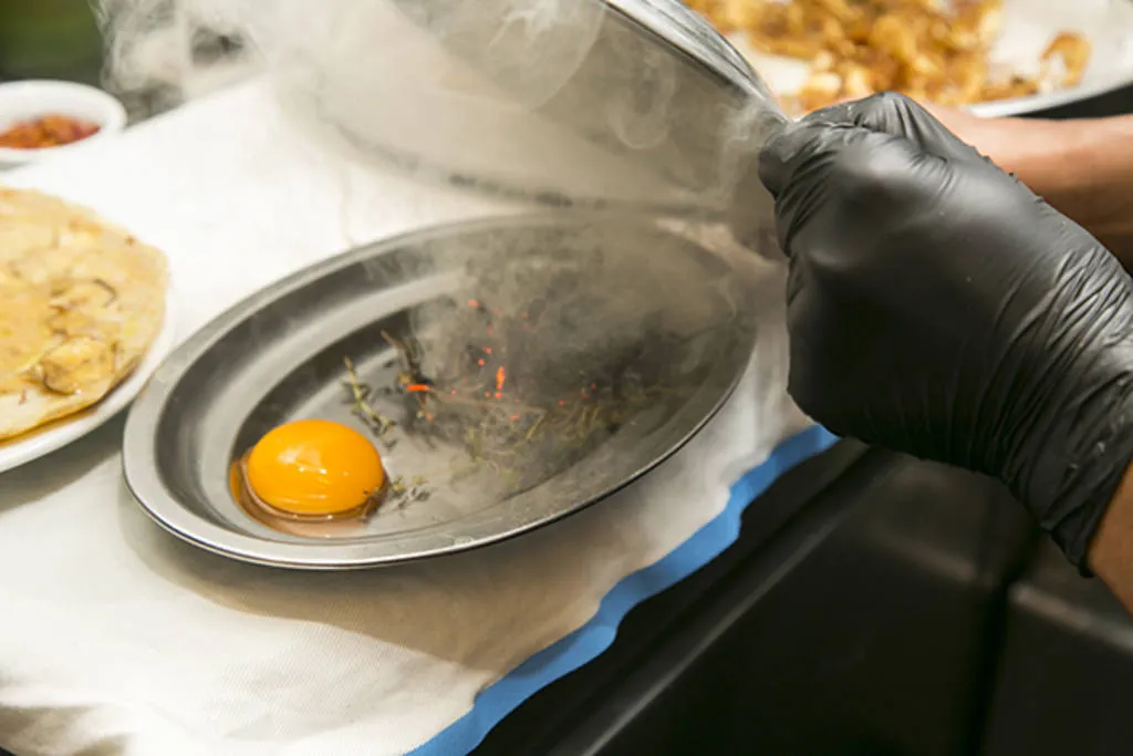 Tortilla abierta de chips de alcachofa, jamón ibérico y yema ahumada al romero