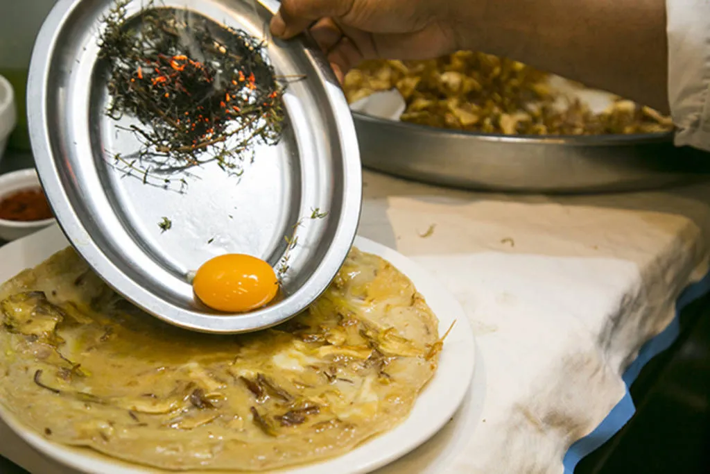 Tortilla abierta de chips de alcachofa, jamón ibérico y yema ahumada al romero