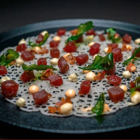 Atún rojo de almadraba con panceta ibérica flambeada y chips de rúcula sobre crujiente de coral