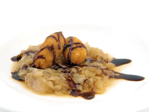 Croqueta ibérica con cama de cebolla caramelizada con baño de Módena