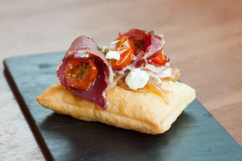 Coca de jamón ibérico, tomates confitados y queso de cabra