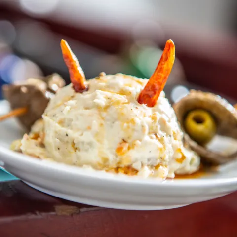 Bola de ensaladilla con dos banderillas de hígado y una aceituna