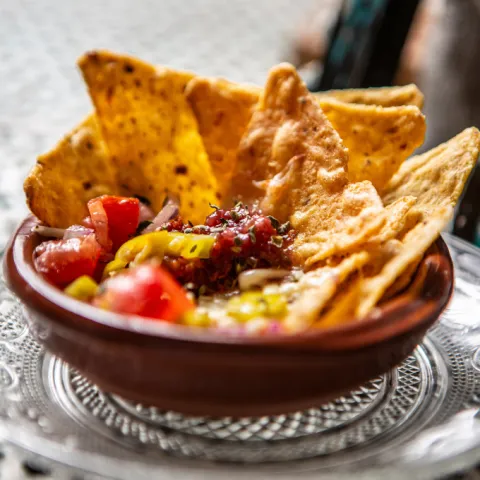 Nachos de maíz con sobrasada, cayena, confitura de higo casera, mozzarella, tomate, cebolla y guindilla