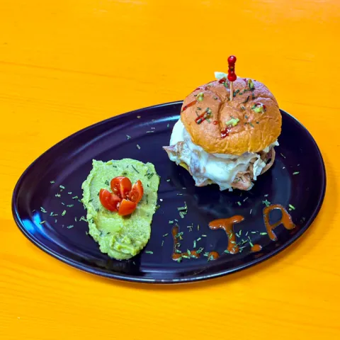 Suculenta mini hamburguesa Pulled Pork, queso Edam, lechuga, tomate y base de salsa guacamole