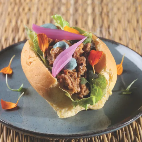 Briojo relleno de cerdo ibérico desmigado con cebolla envinagrada y mayonesa de sriracha verde