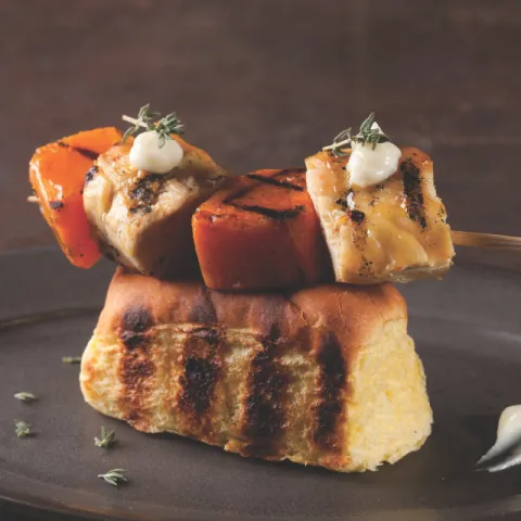 Brocheta de pollo de payés y calabaza del Parc Agrari a la brasa, con alioli de ajos tiernos del Parc Agrari sobre bollo braseado