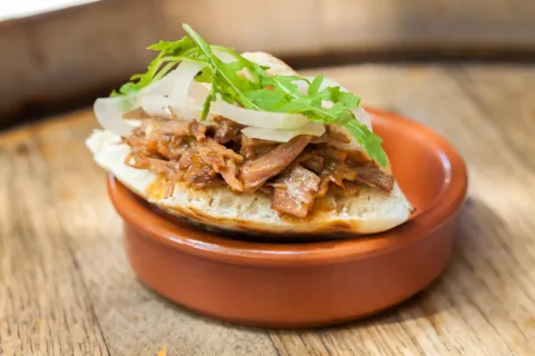 Mini pita de cochinita pibil con cebolla dulce y rúcula 