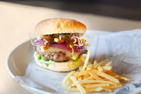 Hamburguesa de ternera ecológica, con rúcula, queso cheddar, cebolla salteada con beicon y salsa hoisin a la mostaza con germinado de remolacha