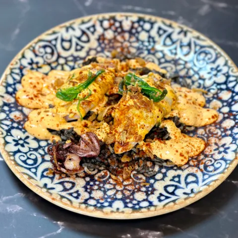 Chipirones con arroz negro, alioli al piquillo, pimentón de La Vera y crujiente de cebolla