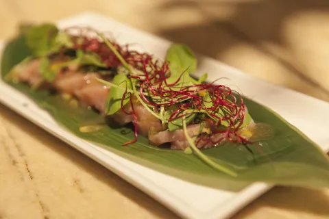 Sashimi de bonito curado con hoja de shiso, berros y ponzu de maracuyá